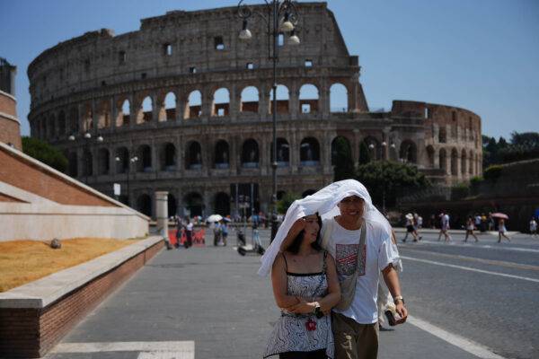 Itália – Turistas se protegem do sol e do intenso calor em Roma, na Itália, enquanto caminham em frente ao antigo Coliseu de Roma, um dos pontos turísticos mais famosos do mundo. Foto: Alessandra Tarantino/AP Photo.