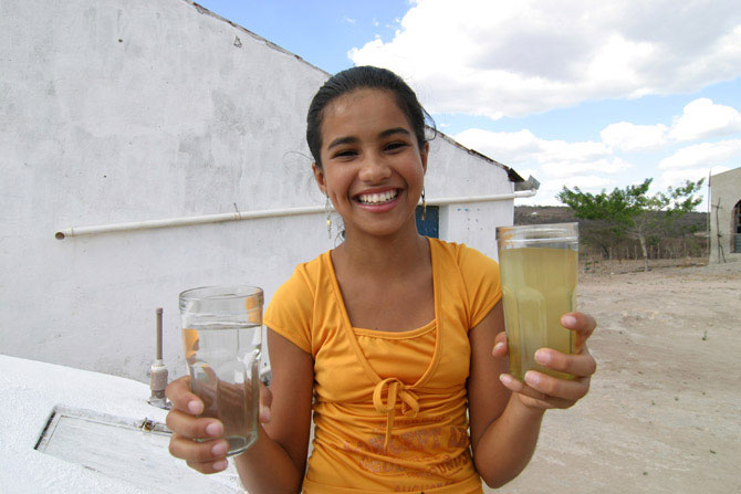 Jovem mostra copo com água barrenta e com água da chuva armazenada na cisterna. Baixo custo e grande efeito no convívio com o clima rigoroso. Foto: ASA / Divulgação